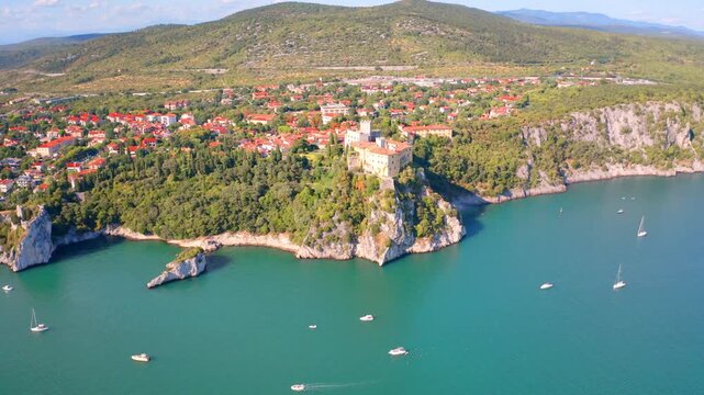 4k drone flight moving to the side footage (Ultra High Definition) of Duino Castle. Wonderful morning scene of Adriatic coast of Italy. Beautiful cityscape of Duino town. Traveling concept background.