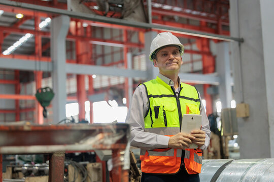 QC engineer uses a tablet to inspect a large industrial or logistic warehouse.