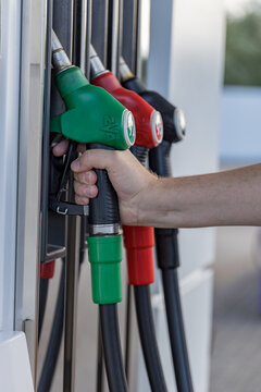 Hand grips green fuel nozzle at station