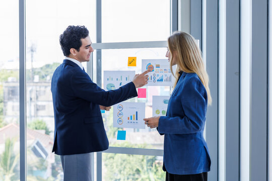 Two businessman and businesswoman partners  in suits smiling standing Talking Discussing presenting financial graph Concept on flip chart board  business expressed embolden and successful concept.