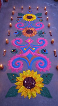 Beautiful rangoli artwork decorated with vibrant colors and lit diyas on the floor for traditional celebration
