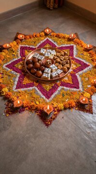 Traditional Diwali celebration with colorful rangoli, sweets, and lit diyas on the floor for the festival of lights