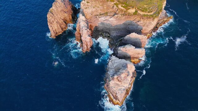 Sea stacks and jagged cliffs on Sao Miguel, Azores, Portugal, above Atlantic Ocean. Close aerial footage of sunlit rock formations