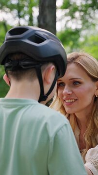 Mother smiles while securing helmet before boy ride bike practice