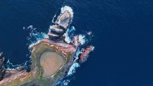 Rocky headland and sea stacks on Sao Miguel, Azores, Portugal. Drone footage of coastal farmland and jagged cliffs surrounded by Atlantic Ocean