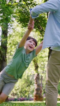 Happy father gently holds cheerful little son and spins around
