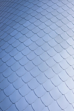 Repeating silver metal shingles create abstract building facade texture.