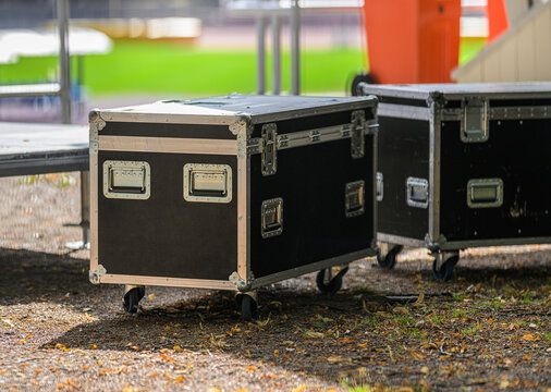 Black road cases stored outdoors for event equipment.