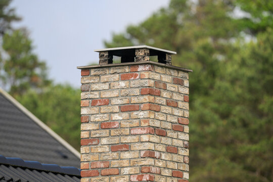 Close view of weathered brick chimney against trees.