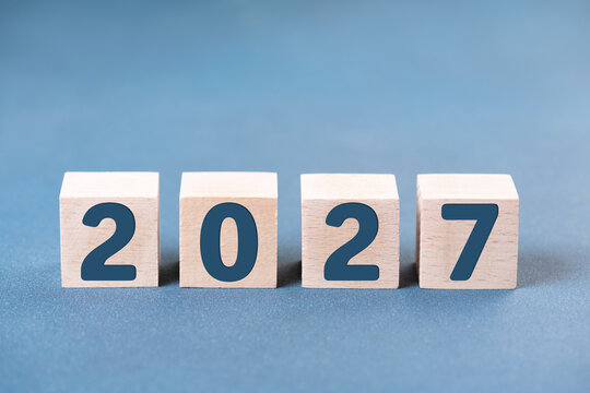 2027 Happy New Year. Wooden cube block change from 2026 to 2027 on blue. Concept 2027 New Year background. Business, resolutions, goals, inspiration, success, ideas