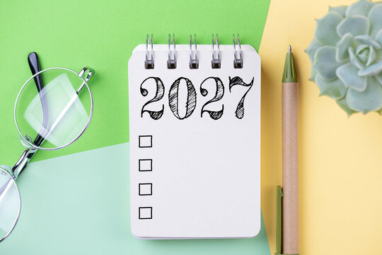 New year resolutions 2027 on desk. 2027 goals list with notebook, coffee cup, plant on table. Resolutions, plan, goals, action, checklist, idea concept. New Year 2027 resolutions, copy space