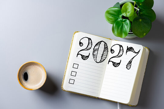 New year resolutions 2027 on desk. 2027 goals list with notebook, coffee cup, plant on table. Resolutions, plan, goals, action, checklist, idea concept. New Year 2027 resolutions, copy space
