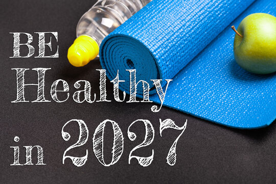 New year 2027 resolutions healthy lifestyle and sport. Be healthy in 2027. Motivation sport goals 2027 with sport equipment shoes, dumbbells, fruit and water bottle on black background