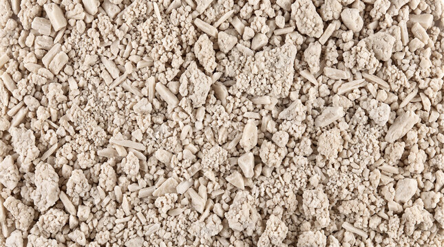 Struvite fertilizer crystals shown as a full-frame field of angular pale mineral particles representing recovered phosphorus fertilizer material