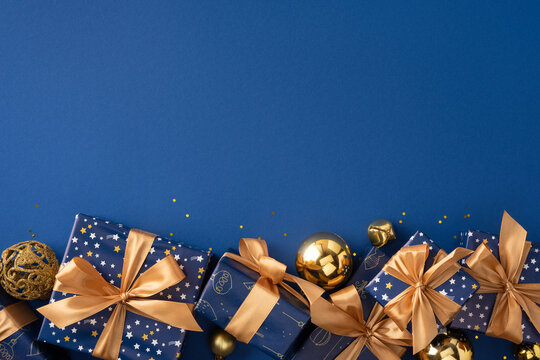 Blue and gold lot of Christmas gifts with ribbons and ornaments for Merry Christmas and Happy New Year on tred dark blue empty space