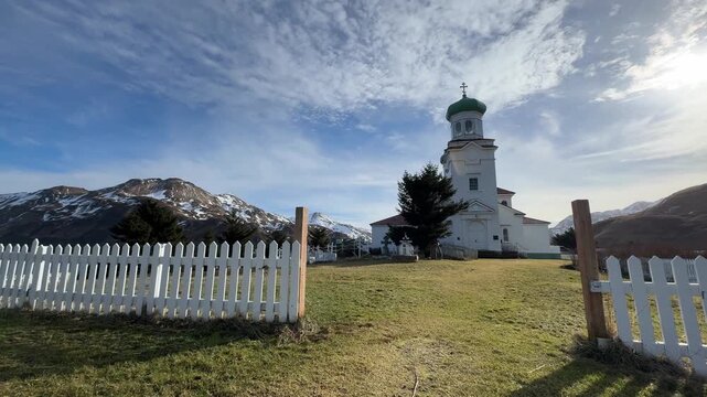 Wide angle perspective shot from an open white gate looking toward the Holy Ascension Russian Orthodox Church in Unalaska, Alaska. 