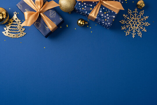 Blue and gold Christmas gifts and ornaments on a festive background for Merry Christmas and Happy New Year on minimal blue copy space