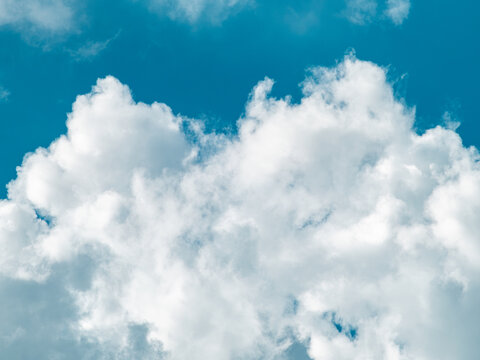 Fluffy white cumulus cloud rising against vivid blue sky, clean minimal weather background with bright natural daylight