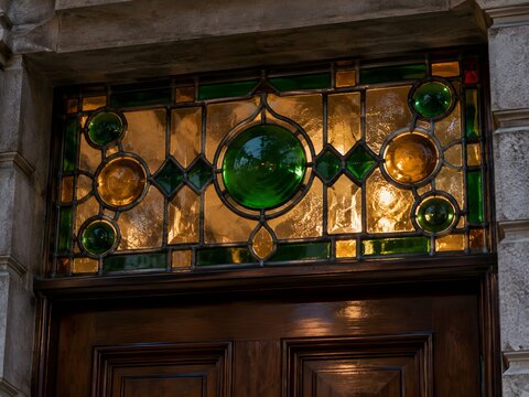 Stained glass transom with emerald and amber roundels over panelled wooden door