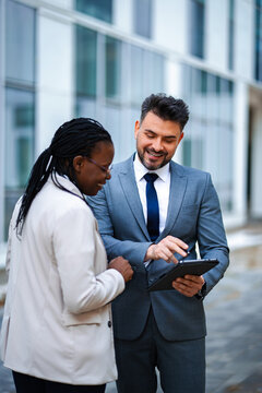 Diverse business professionals collaborating using digital tablet outdoors