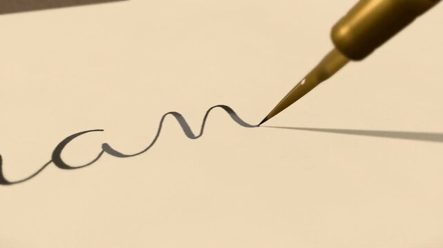 Gold pen writing thank you in cursive calligraphy with heart flourishes on cream paper