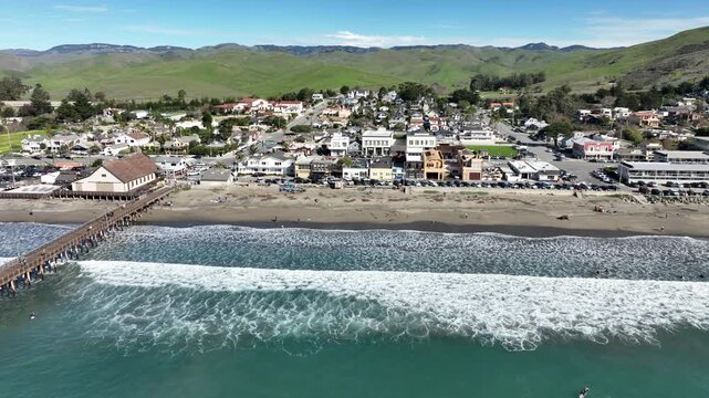 Cayucos, California, USA - Aerial View of Cayucos Pier With Waves Crashing on Sandy Beach, Ocean Avenue Residential Homes, Coastal Hills and Pacific Shoreline in San Luis Obispo County