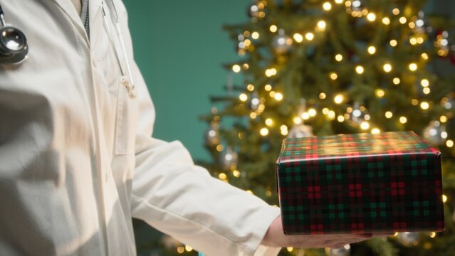 Doctor Donates a Christmas Gift Box to His Patients Against Tree In Hospital