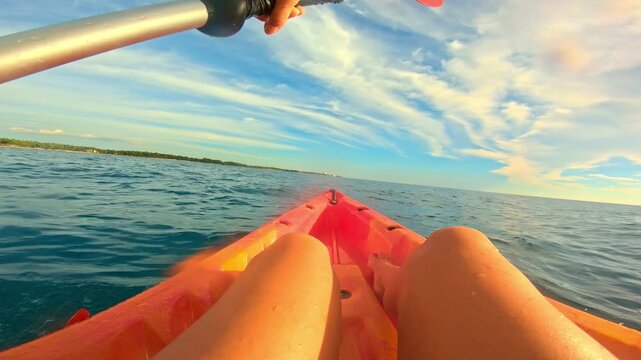 A person paddles through calm blue waters on a sunny day, embracing an active lifestyle. The sea kayaking adventure captures serene surroundings and a sense of freedom.