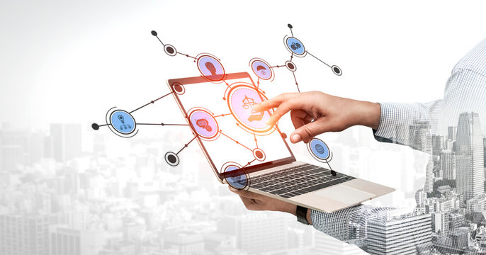 A hand reaching out to interact with a laptop showing digital connections. This image symbolizes modern technology, networking, and innovative business solutions in a dynamic urban setting. Tessel