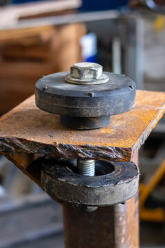 Heavy duty rubber vibration isolator dampener mount installed on rusty steel bracket.