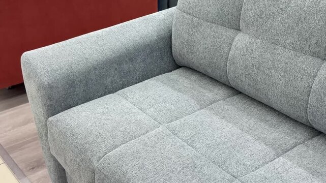 Gray fabric-upholstered sofa corner with quilted texture, modern furniture piece in home interior setting, ideal for living room, seating, and lifestyle concepts.