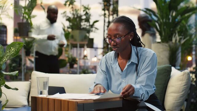 Businesswoman reads project notes in rooftop lounge