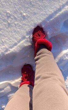 Cozy winter walk with red boots in fresh snow