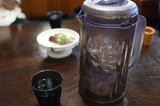 氷入りのお冷のピッチャーとコップ。飲食店の木製テーブル