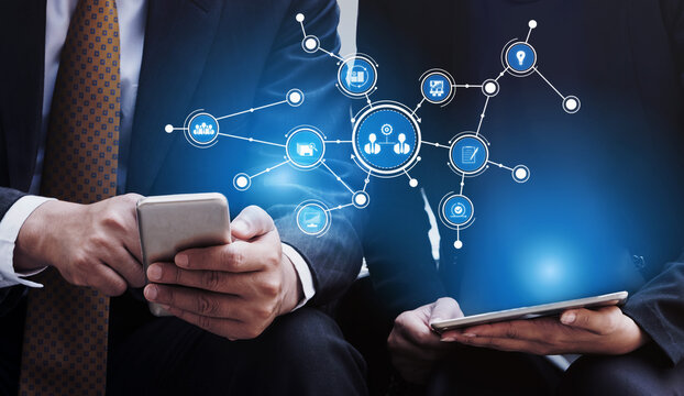 Two business professionals engage with smartphones and tablets, utilizing digital tools to enhance communication and networking in a modern corporate setting. Tessel
