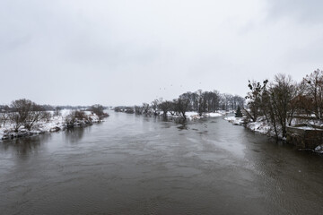 Zimowa panorama rzeki Odry w popołudniowych godzinach pochmurnego szarego zimowego dnia pełnego śniegu dnia w Zachodniej Polsce © mbugajsky
