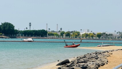 Red inflatable rubber boat moored on sandy beach with rock embankment along turquoise Red Sea water in Jeddah, Saudi Arabia © Muhammad