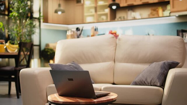 Empty living room with laptop on wooden coffee table and contemporary couch, creating a modern rustic interior with open space and no people.