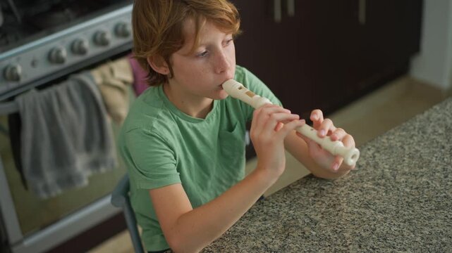 A little boy learns to play the flute at home, practicing with focus and enthusiasm in a cozy, warm setting. A charming scene of early musical exploration, creativity, and childhood growth.