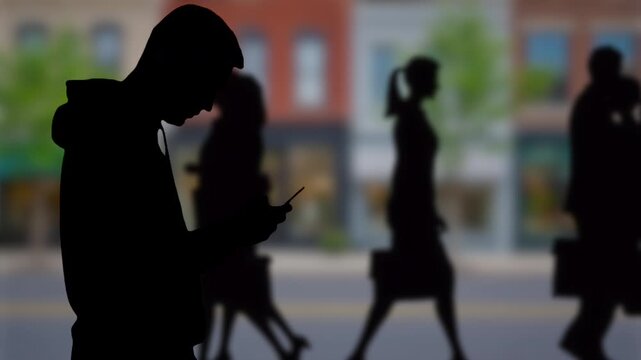 Man in silhouette looking at smartphone downtown