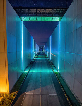 Illuminated tunnel road at night with blue cyan lighting and futuristic architectural perspective under starry sky