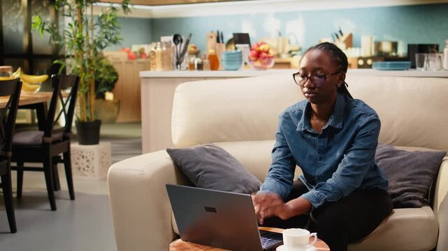 Woman freelancer stretches on couch and relaxes back muscles while dealing with stiffness and physical fatigue from remote work, experiencing strain and neck ache discomfort while working at home.
