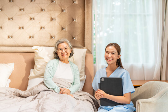 Asian female gerontological nurse visit senior woman patient at home, talking and using digital tablet health check, elderly care, home caregiver, medical healthcare consultation for healthy aging