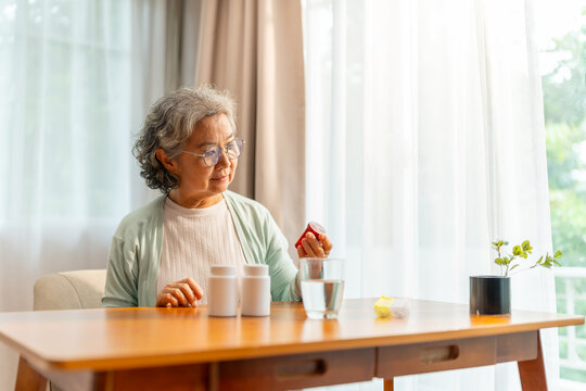 Senior woman taking medicine from pill bottle at home, elderly healthcare medication management, daily treatment and prescription drugs, health support and chronic disease care for aging lifestyle