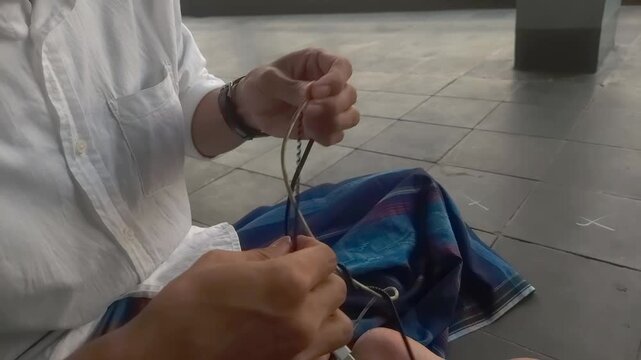 Close-up of hands meticulously working with string or wire, focused on a craft