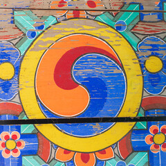 Vintage weathered dancheong wooden ceiling mural featuring colorful traditional samtaegeuk symbol at a Buddhist temple in South Korea. © 완수 안