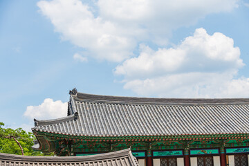 Curved hip and gable tiled roof with dragon head ornament and painted murals at a Buddhist temple in South Korea. © 완수 안