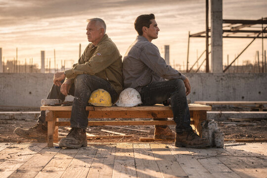 Two Construction Workers Sitting Back to Back at Sunset