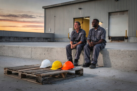 Warehouse Workers Relaxing on Loading Dock at Sunset Break