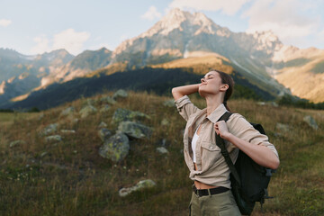 Fototapeta premium woman hiking outdoors in a mountain meadow with a backpack, enjoying sunlight and nature, a casual lifestyle moment on a scenic trail with clear sky